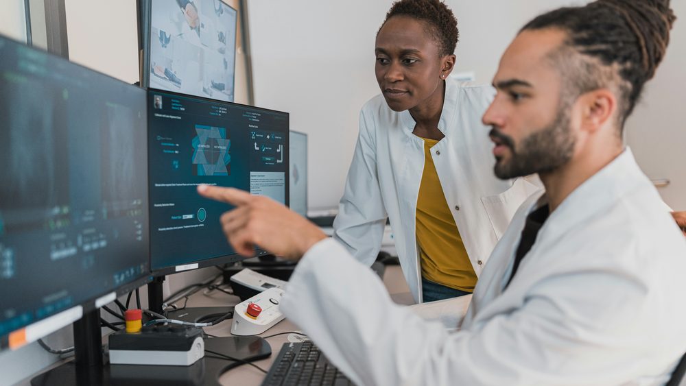 Clinicians reviewing data on monitors at a workstation